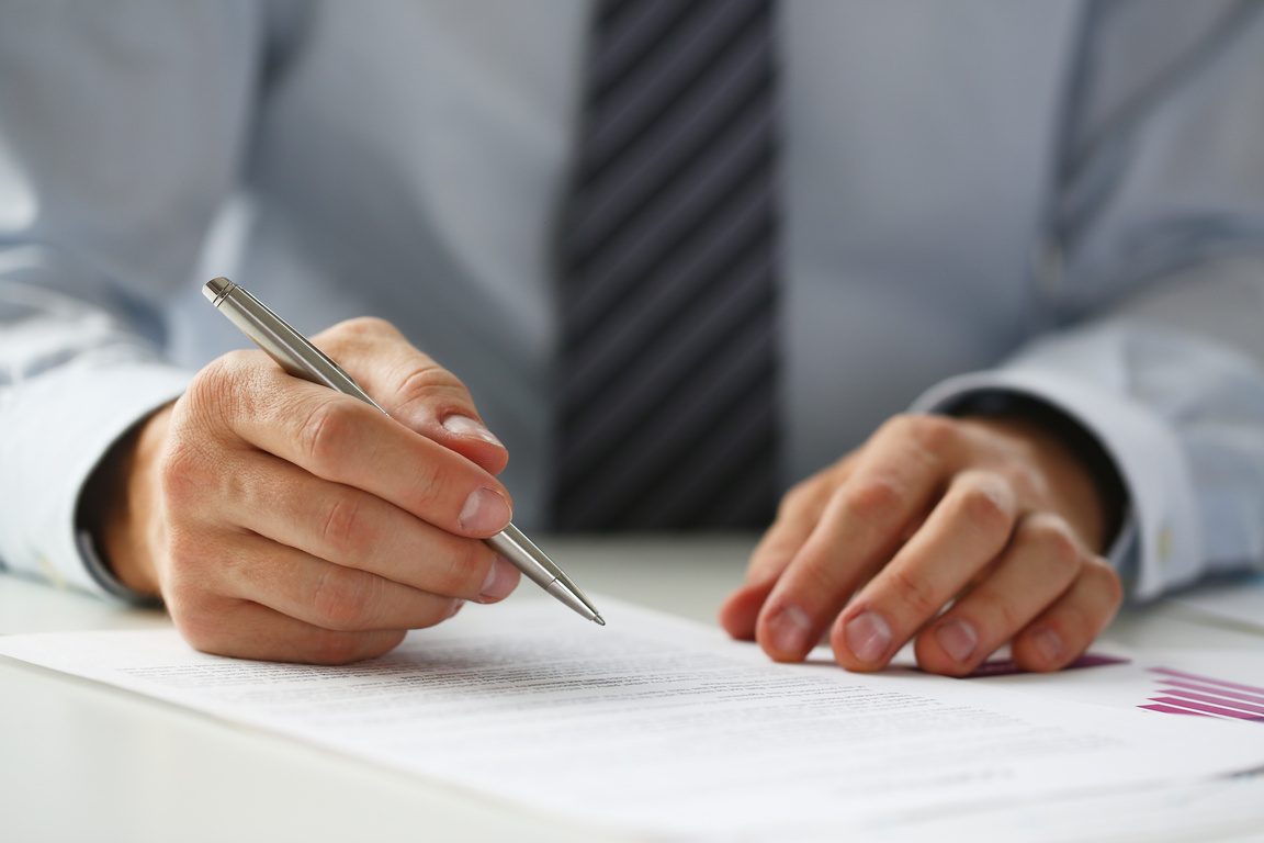 Hand of Businessman in Suit Filling and Signing with